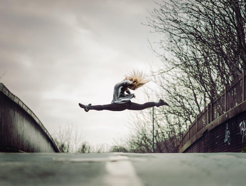 A woman jumping in the air doing the splits representing agility.