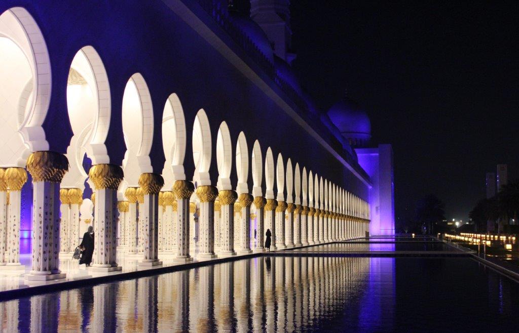 The light from the arches of a building reflected in water.