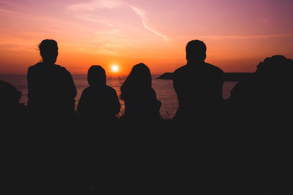 A silhouette of a family looking at a sunset.