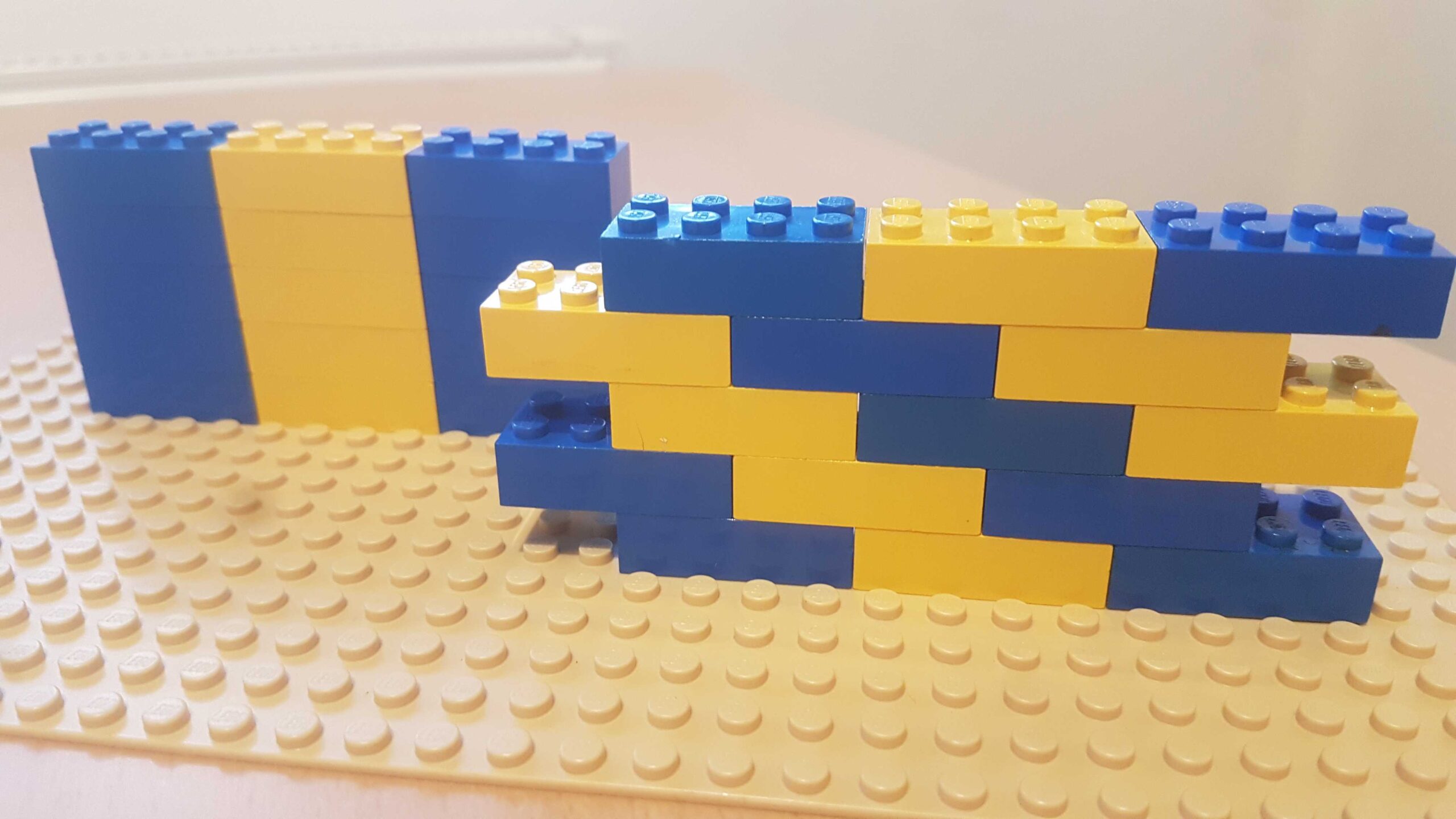 Blue and yellow Lego pieces built up in a stack in two different ways.
