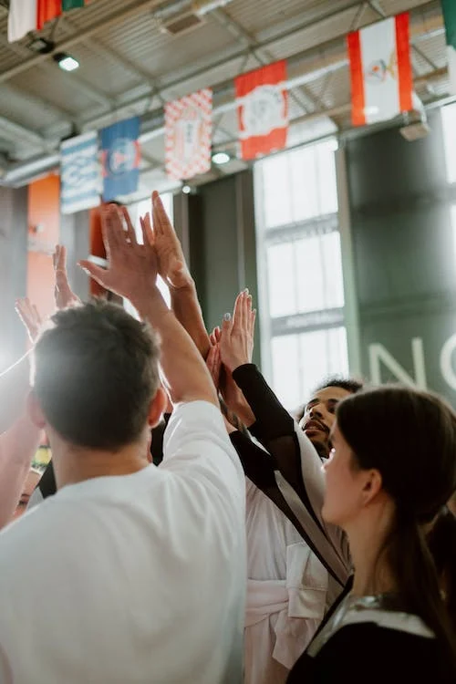 Group of people raising their hands in the middle with many different flags in the air.